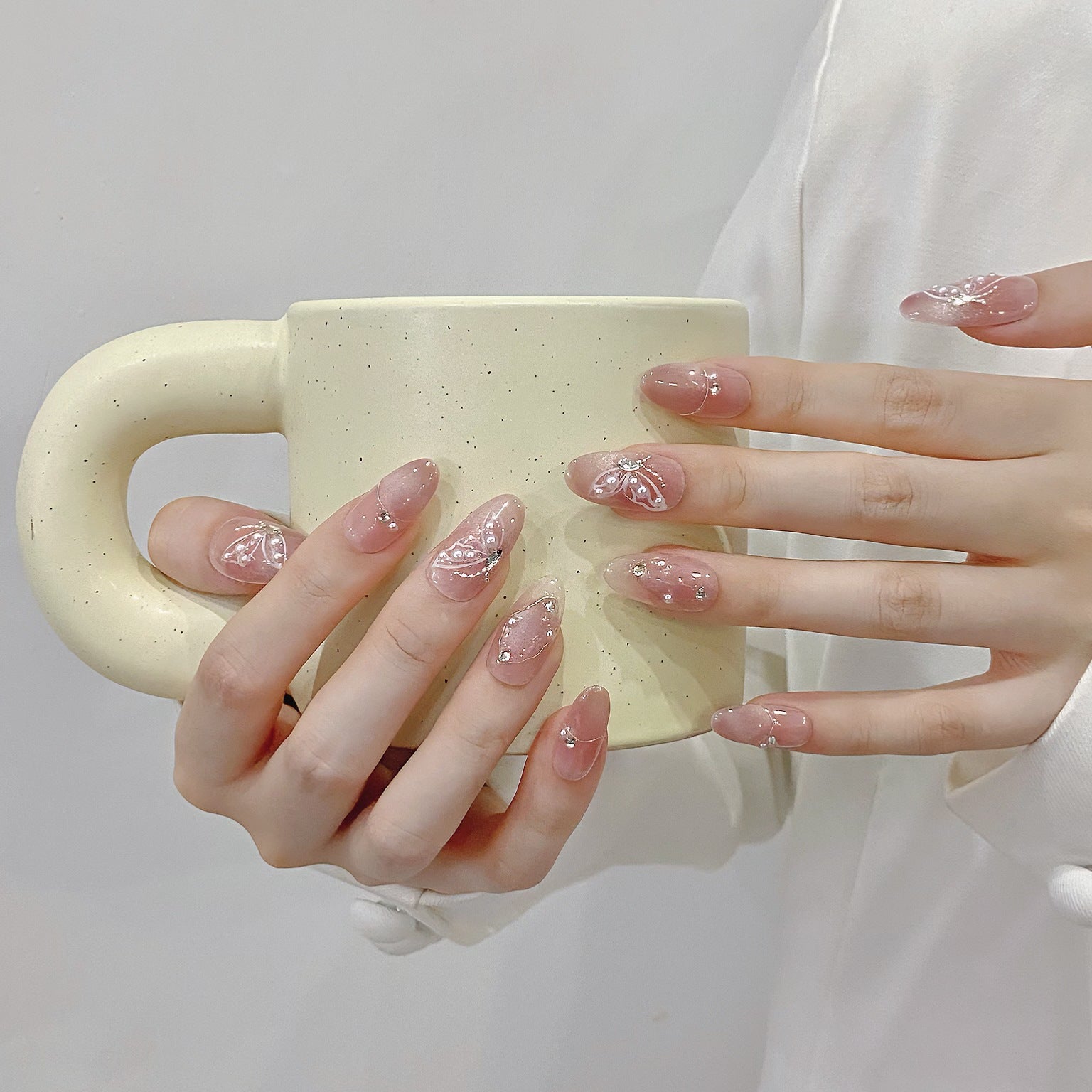 Blush pink medium oval press-on nails with butterfly pearl and crystal details